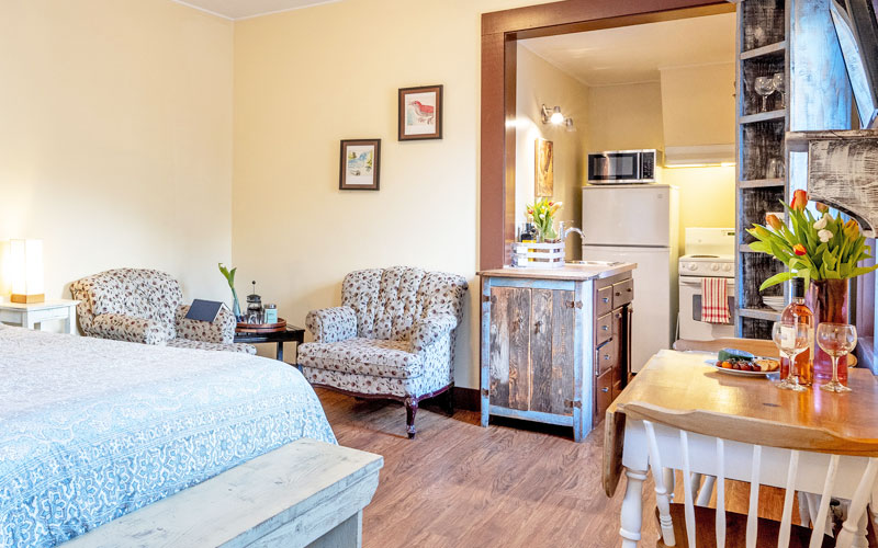 Full studio interior of the Herridge Suite featuring heritage-inspired decor, rustic wood furniture, and a well-appointed kitchenette and dining area.